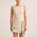 The Garden Dress in Light Apricot, front on-body view showing the side-tie wrap panel, forest Vé mark, and A-line skirt.
