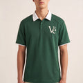 The Court Polo in Dark Green, front on-body view showing the white contrast collar, sleeve trim, and cream Vé chest monogram.