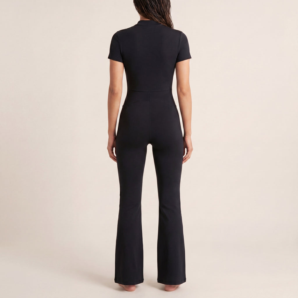 The Studio Jumpsuit in Black, back on-body view showing the clean fitted silhouette, waist seam, and flared leg.