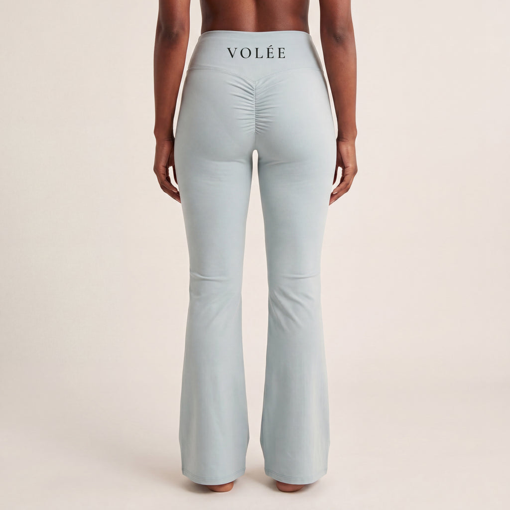 The Flare Legging in Gray, back on-body view showing the VOLÉE waistband wordmark, ruched back seam, and flared leg.