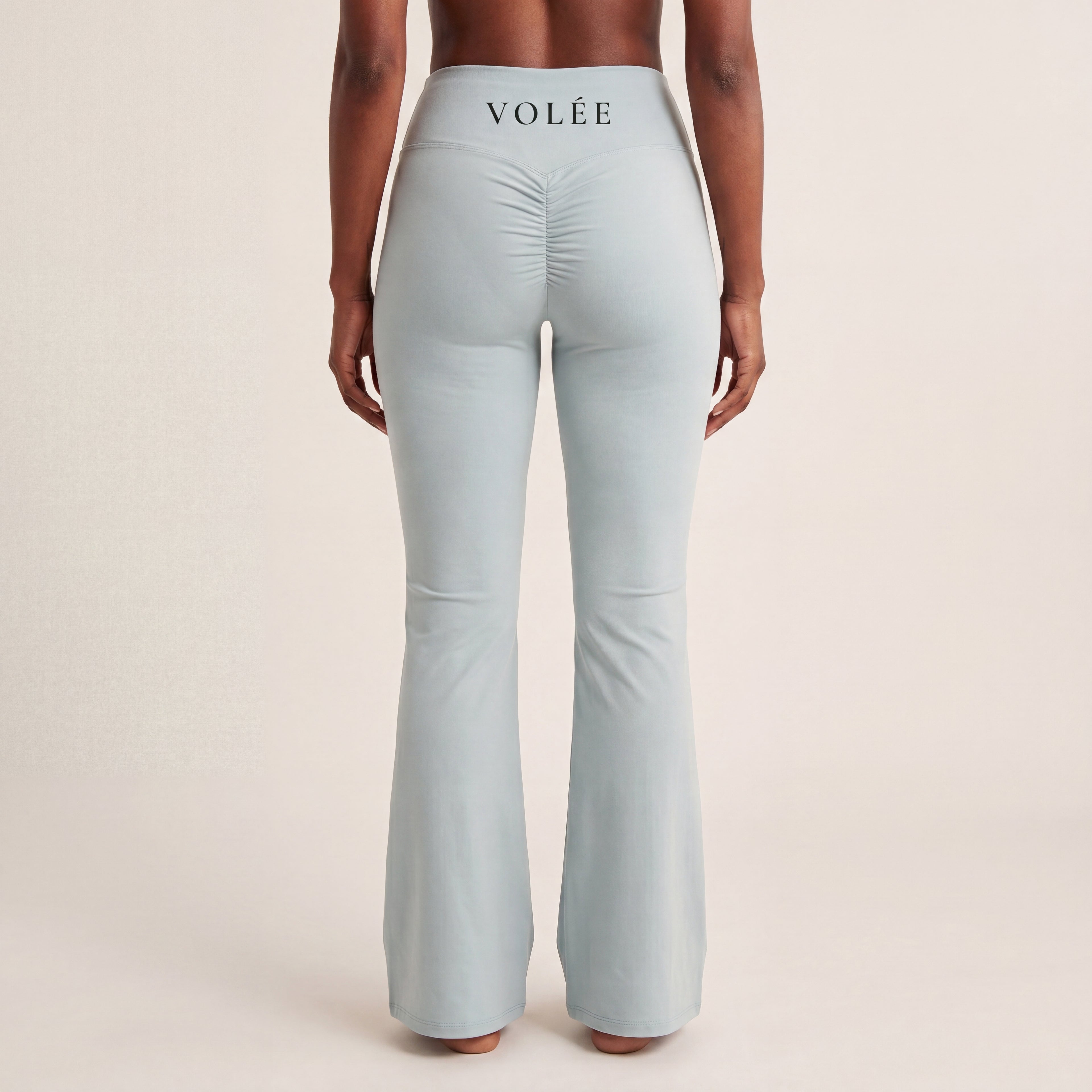 The Flare Legging in Gray, back on-body view showing the VOLÉE waistband wordmark, ruched back seam, and flared leg.